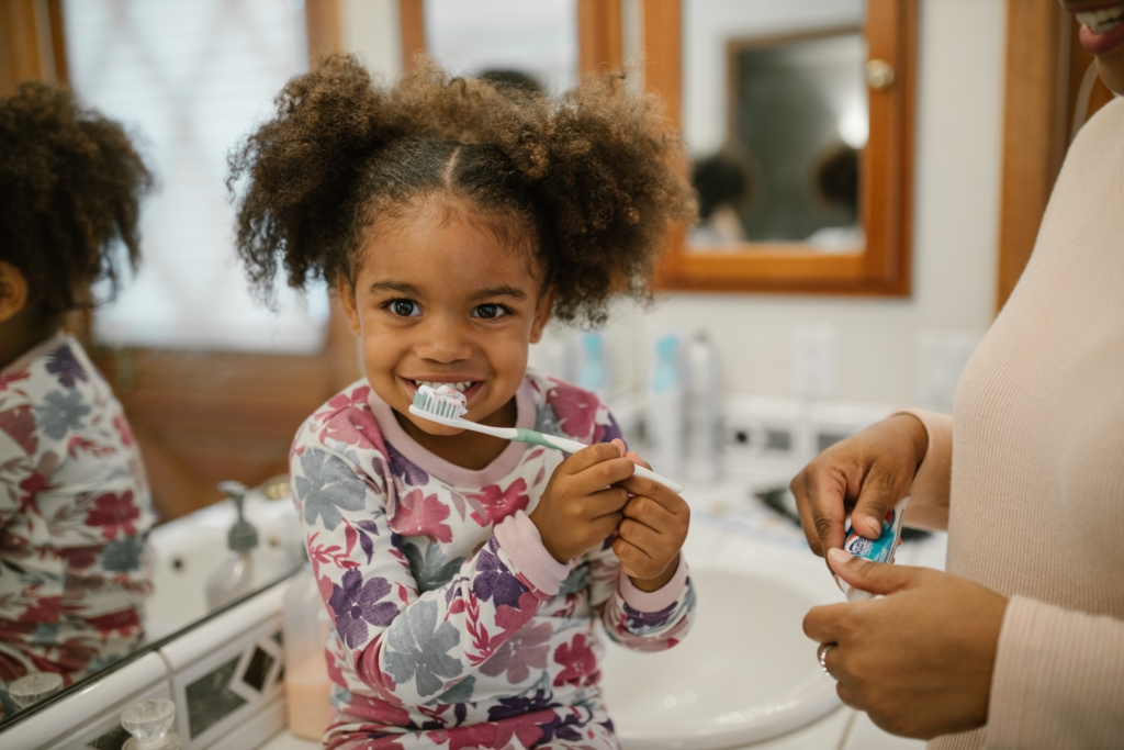 Little girl with pigtails brushing teeth