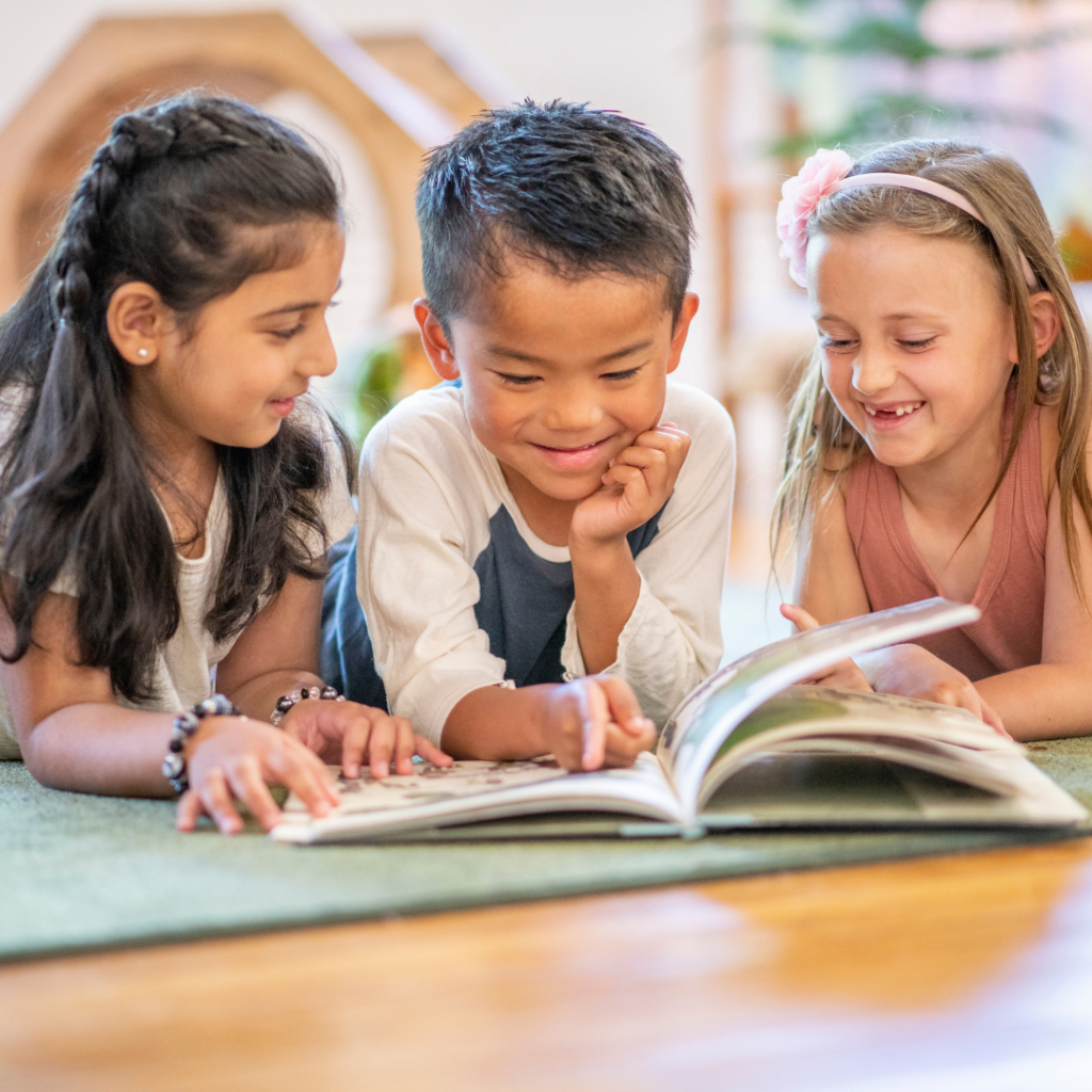 Three children read a book together.