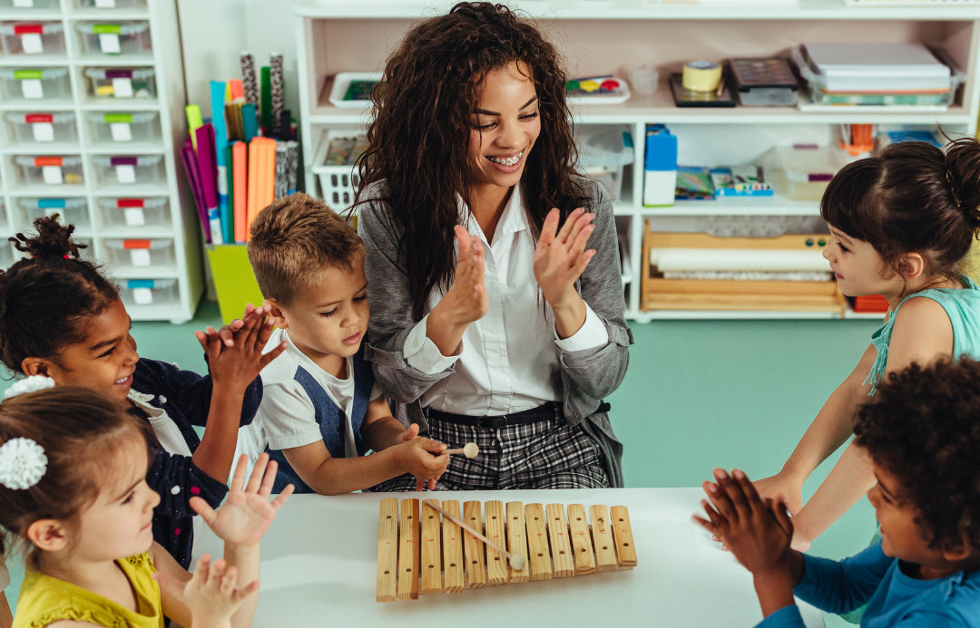 A child care teacher and her students play with a xylophone.