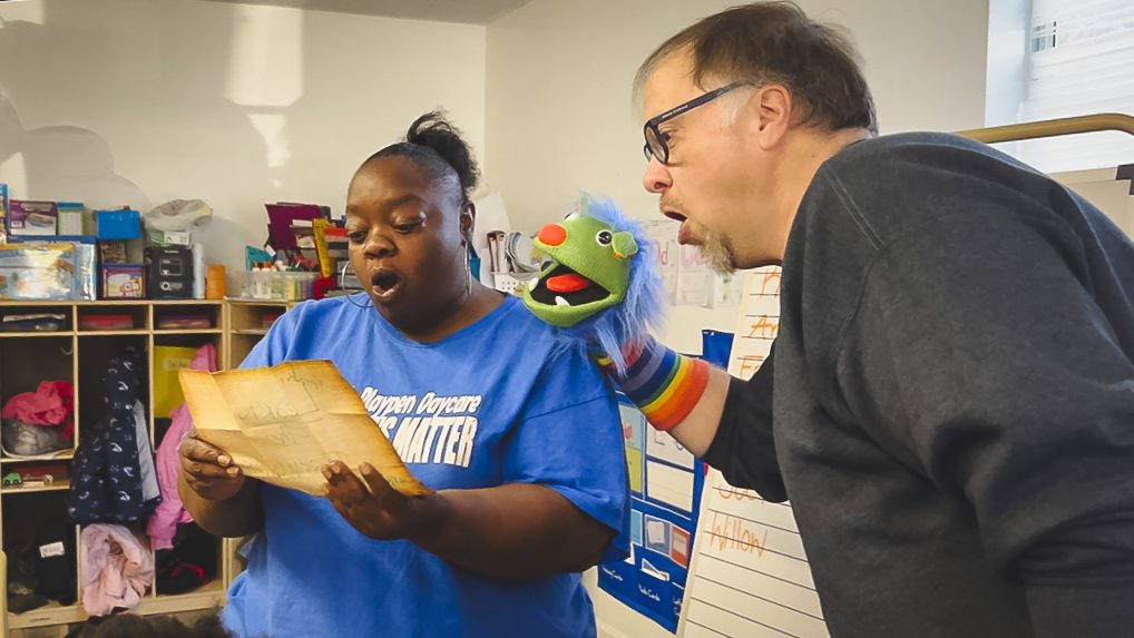 Man holding text and child care teacher reading