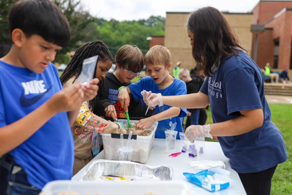 Children gathered around a bucket of sand