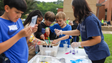 Children gathered around a bucket of sand
